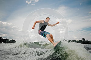 Handsome wakesurf rider jumping on the waves of a river photo