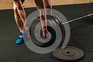 Handsome weightlifter preparing for training with barbell