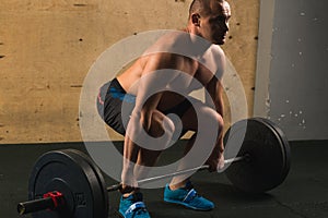 Handsome weightlifter preparing for training with barbell