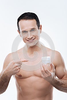 Handsome well built man pointing at the cream bottle