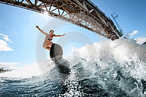 Handsome woman skillfully bounces on the wave with surfboard photo
