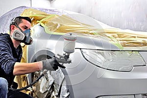 Handsome worker painting a car. No model real mechanic