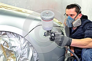 Handsome worker painting a car. No model real mechanic. With selective focus