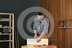 Handsome working man using hand saw. Home repair