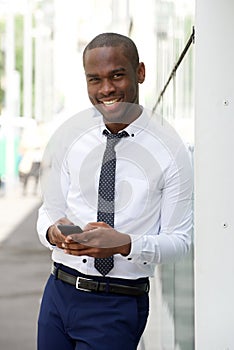 Handsome young african american businessman smiling with mobile phone in city