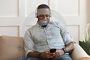 Handsome young african american guy wearing wireless bluetooth headphones.