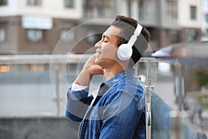 Handsome young African-American man with headphones listening to music on street