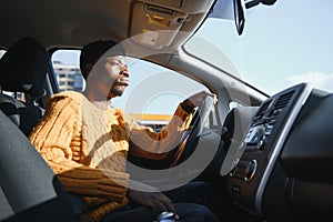 Handsome young African American man in his new high-tech electric vehicle while drinking. Self driving vehicle concept