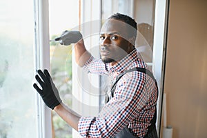 handsome young african american man installing bay window in new house construction site