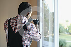 handsome young african american man installing bay window in new house construction site