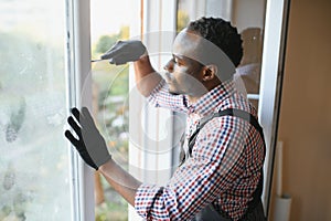 handsome young african american man installing bay window in new house construction site