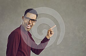 Handsome young african american man laughing pointing finger on copy space