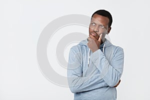 Handsome young African American man looking up with thoughtful and skeptical expression