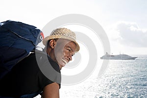 Handsome young african american travel man smiling by the sea with cruise ship in background