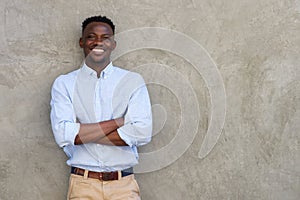 Handsome young african man smiling with arms crossed by wall