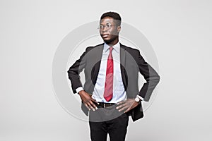 Handsome young African man in suit while standing against grey background