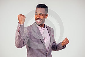 Handsome young Afro American businessman in classic suit rejoicing and exulting a lucky one winner on white background