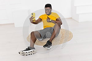 Handsome young afro american male is sitting in front of camera, making a video about sport exercises, healthy lifestyle