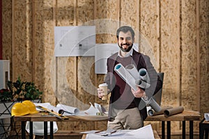 handsome young architect with coffee to go and rolled blueprints