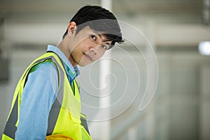 Handsome young Asian engineer in yellow reflective vest  working  in constrction site