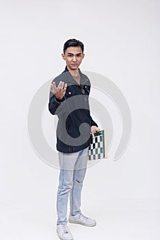 A handsome young asian man holding a chess board. A rookie talented chess player. Isolated on a white background