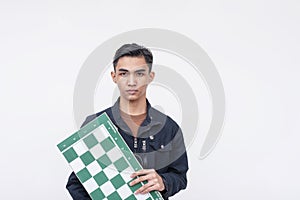 A handsome young asian man holding a chess board. A rookie talented chess player. Isolated on a white background