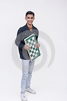 A handsome young asian man holding a chess board. A rookie talented chess player. Isolated on a white background