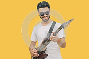 Handsome young asian men playing guitar and  listen music with headphones   on yellow background