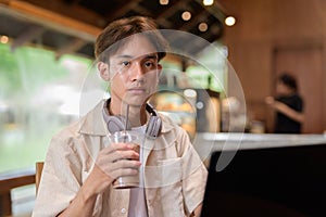 Handsome young non binary man sitting in cafe restaurant using laptop computer