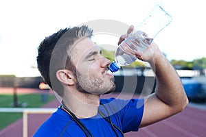 Handsome, young athlete drinking water