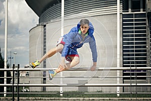 Handsome young athlete jumping over the fence