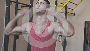 Handsome young athlete in sportswear stretching hands before training indoor. Muscular sporty man warming up before hard