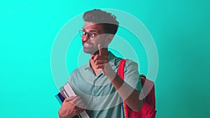 handsome young bearbed indian man with eye glasses in blue cotton t-shirt with orange rainbow backpack in studio