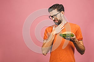 Handsome young man refusing unhealthy burger isolated over pink background. Diet concept. With copy space for text