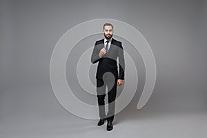 Handsome young bearded business man in classic black suit shirt tie posing isolated on grey background studio portrait