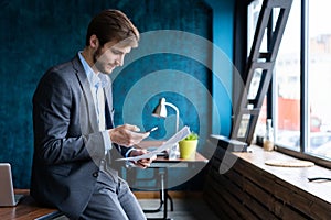 Handsome young bearded business man in office using mobile phone indoors.