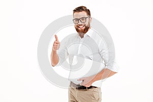 Handsome young bearded man holding laptop showing thumbs up.