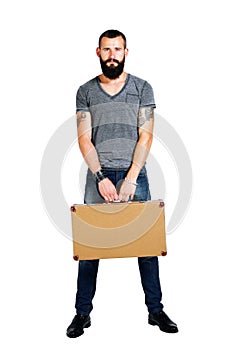 Handsome young bearded man holding a suitcase