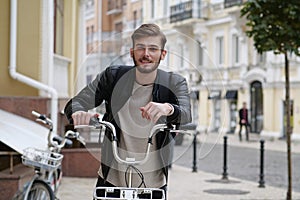 Handsome young bike messenger with backpack and bicycle looks at camera