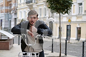 Handsome young bike messenger with backpack and rental bicycle looks at camera