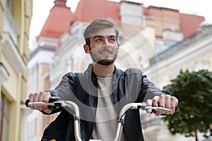 Handsome young bike messenger sits on bicycle and looks ahead