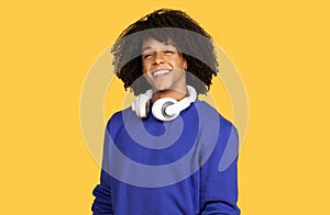 Handsome Young Black Guy With Headphones Around Neck Posing Over Yellow Background