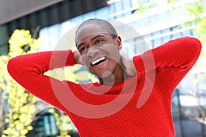 Handsome young black man laughing with hands behind head