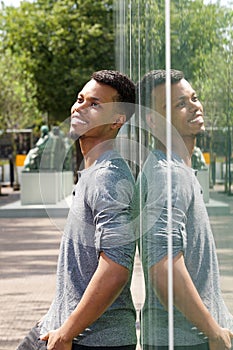 Handsome young black man leaning against window with reflection