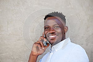 Handsome young black man making a phone call by wall