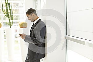 Handsome young black man with mobile phone in office