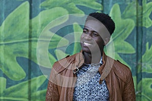 Handsome young black man smiles in front of painted wall