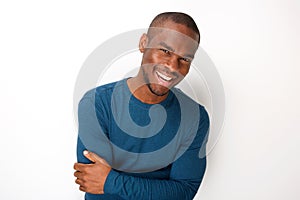 Handsome young black man smiling with arms folded by white background