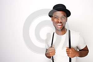 Handsome young black man smiling with hat and suspenders against white background