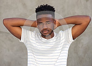 Handsome young black man standing with hands behind head